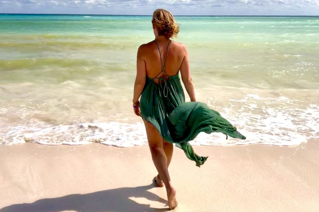 Liane den Hartog loopt in een groene jurk de zee in.